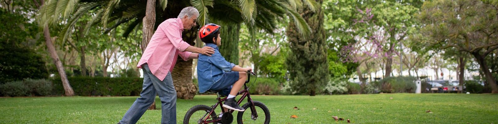 A grandfather teaching his grandson to ride a bike