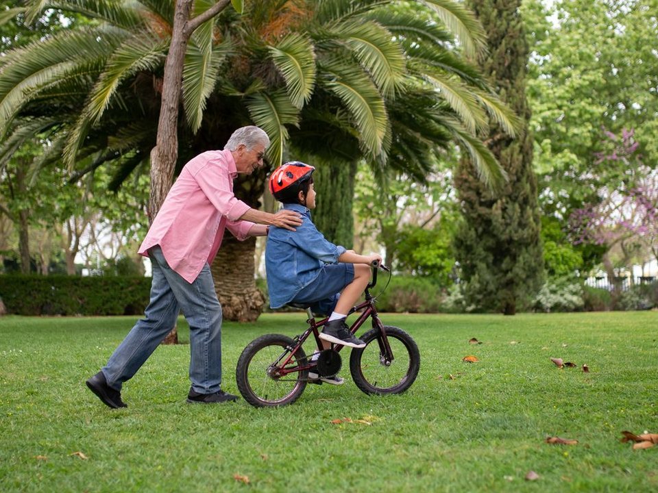 A grandfather teaching his grandson to ride a bike