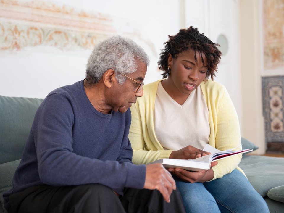 A father and adult daughter reading together on the couch